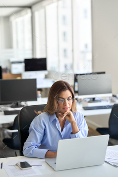 Busy aged alternate lady using laptop laptop working in office. Vertical