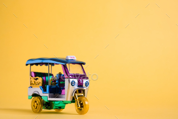 Model Toy tuk tuk remoted on yellow background. Thai mature taxi in Bangkok Thailand. Memento