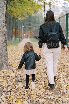 Mother and fairly woman proceed holding palms alongside a mesh fence in an autumn park. Discount plan