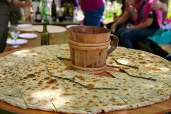 Soparnik – extinct Croatian meals on big wooden plate with wooden mug throughout the heart