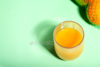 A glass of palatable orange juice is positioned on a inexperienced desk alongside new oranges