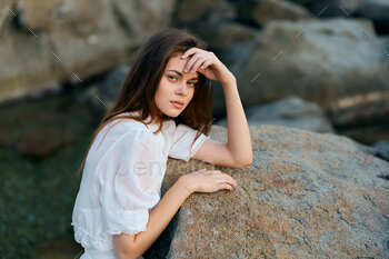 Aloof younger lady on coastal rock, considering the ocean with class and charm