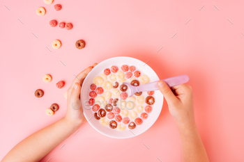 Breakfast of corn rings with milk on pink background