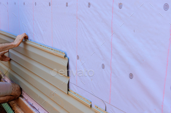 In job of putting in vinyl siding on authentic home facade, a handyman installs vinyl PVC siding