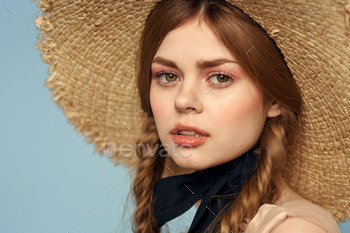 Woman in a straw hat portrait halt-up pigtails gratifying crimson hair blue background