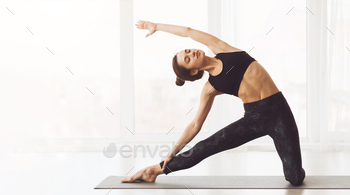 Younger Lady Working towards Prolonged Facet Angle Pose in Yoga Studio