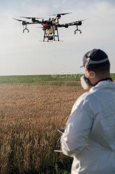 Drone operator, distinctive farmer flies drone over agricultural fields