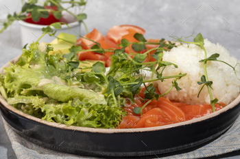 Salad bowl with rice, salmon, tomatoes, cucumbers and avocado. Poached egg.