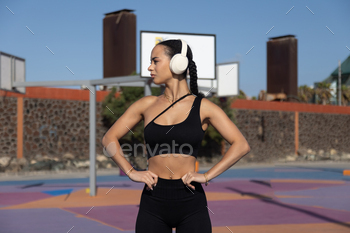 goal accurate-looking out younger sportswoman alongside together with her fingers on her waist with vibrant background of basketball courtroom