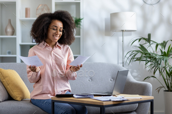 Tickled woman managing funds at dwelling with laptop computer and paperwork