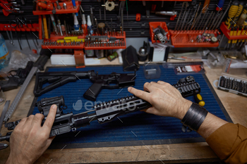 Man disassembles and cleans a rifle in a workshop