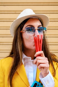 Hipster and commonplace woman kissing crimson sweet and having a gaze to the digicam. Chilly and humorous portrait.