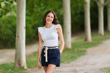 A woman sporting a white shirt and blue shorts is strolling in a park