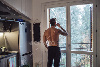 Mid grownup man with tattoos thrilling espresso and having a request out by means of kitchen window