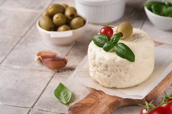 Ricotta cheese. Handmade Ricotta cheese with basil, garlic, tomatoes and inexperienced olives on parchment p