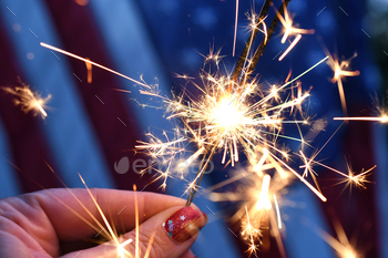 Conserving sparklers in entrance of an American Flag to rejoice patriotic trip – the 4th of July USA