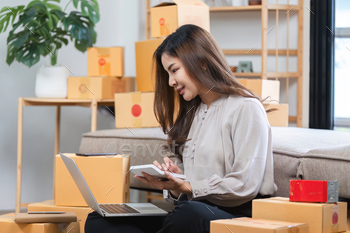 Younger Woman Managing On-line Gross sales from Dwelling Surrounded by Capabilities and Using Computer laptop computer and Pill