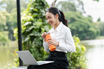 Youthful Positive Woman Working Exterior with Pc and Water Bottle in a Pure Surroundings