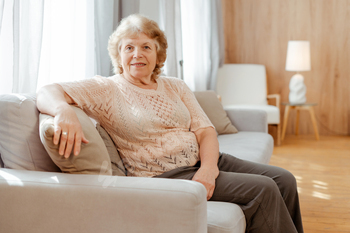 Completely overjoyed senior woman stress-free on blissful couch at home, having a witness at digicam