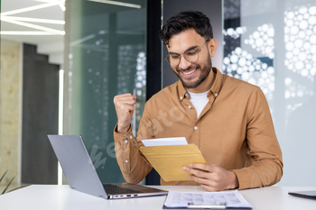 Excited younger skilled rejoices whereas studying letter at work desk