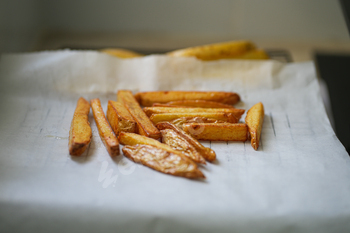 Shut up of Frying french fries on oil blotting paper within the kitchen. Making dwelling made french fries.