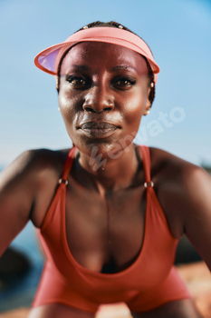 Assured girl in sporty attire watching on the digital camera towards a mental blue sky background