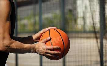 Basketball orange ball in man hand on sport courtroom. Sport background.