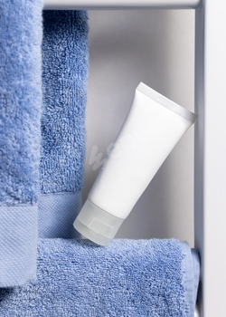 White squeeze cream tube on blue towel on toilet shelf,  pack up, beauty mockup