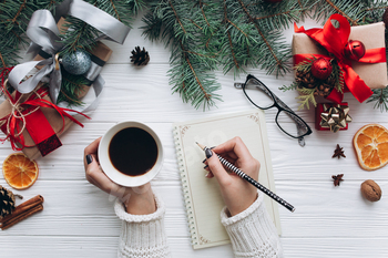 Christmas picket background. Girl spicy espresso and writing to achieve guidelines on basic pocket book.