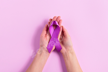 Purple most cancers ribbon in womens palms on crimson background