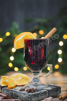 Glass of pink wine mulled wine with cinnamon and orange on a reducing board on a desk .