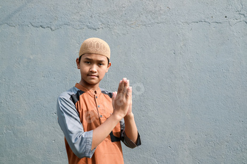 a youthful asian muslim stands with a welcoming gesture