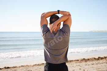 younger man does exercise routines on the shoreline begin air